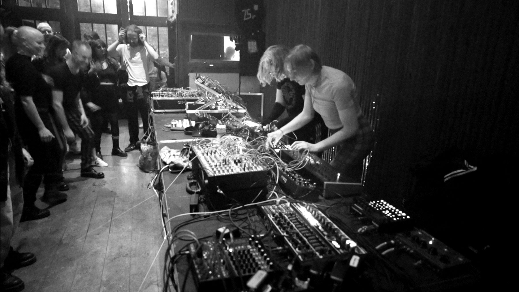 Catenation live behind a long table of modular synthesizers, audience dancing